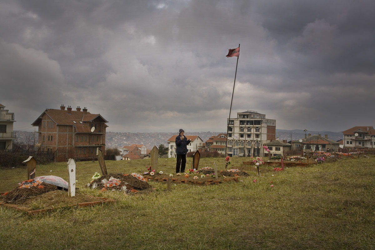 An old man prays at a small KLA cemetery up on Martyrs' Hill in Pristina.
