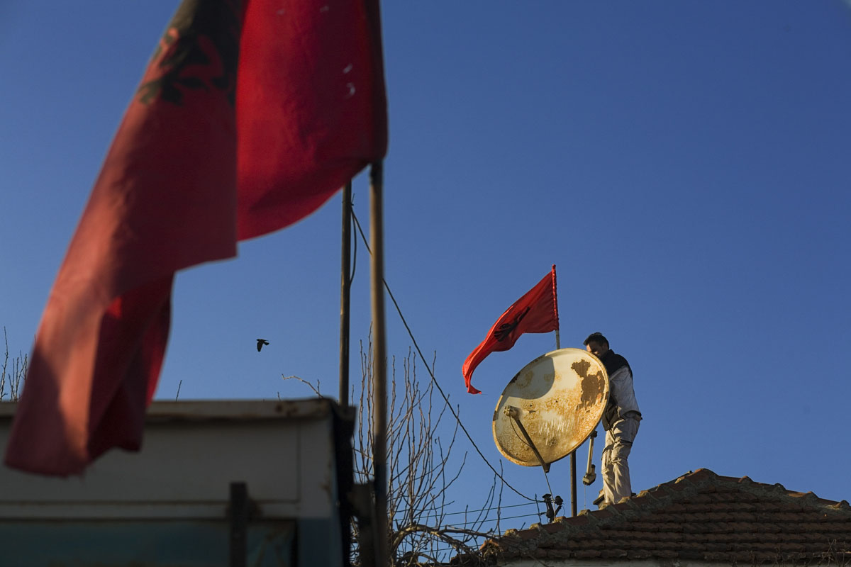A man puts up an Albanian flag on his house in Pristina on independence day.