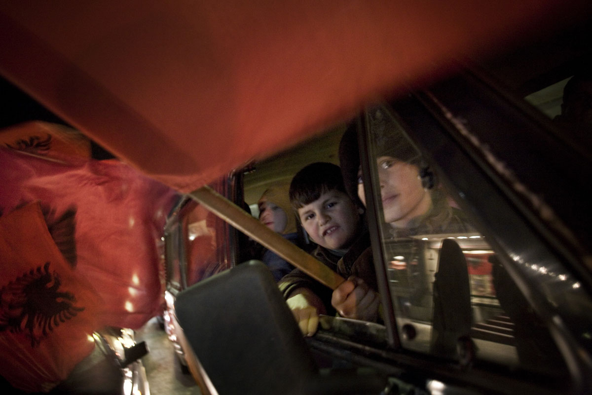 Children wave the Albanian flag from a car in Pristina, the evening before the declaration of independence.